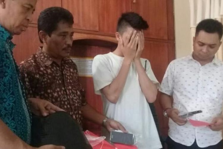 Abi Rizky (menutup wajah) bersama barang bukti saat diamankan di Mapolsek Sungai Raya (10/3/2017)