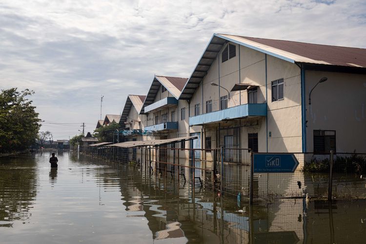 Seorang karyawan berjalan menerobos banjir limpasan air laut ke daratan atau rob di kawasan industri Pelabuhan Tanjung Emas Semarang, Jawa Tengah, Jumat (27/5/2022). Karyawan sejumlah pabrik setempat mulai membersihkan sisa-sisa banjir rob di dalam pabrik yang berangsur surut, meskipun air rob masih merendam sejumlah titik akses keluar - masuk kawasan industri pelabuhan dengan ketinggian bervariasi hingga sekitar 70 sentimeter.