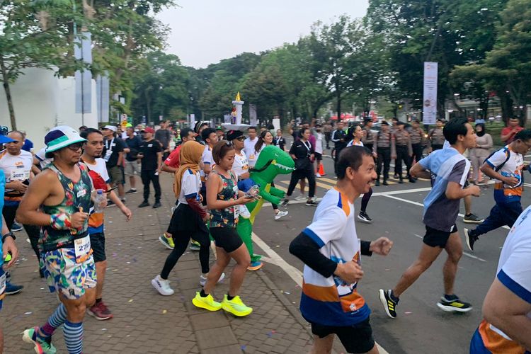 Seorang pelari berkostum dinosaurus di acara Run the City LPS Half Marathon berlangsung di Hutan Kota Plataran kawasan Gelora Bung Karno (GBK), Senayan, Jakarta, pada Sabtu (1/7/2023).