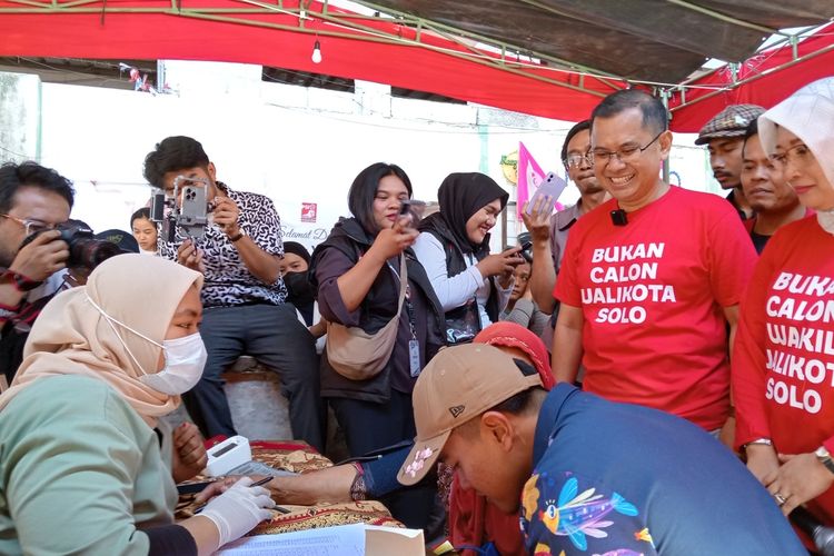 Pasangan calon wali kota dan wakil wali kota Bandung Arfi Rafnialdi-Yena Iskandar Ma'soem memakai kaos merah bertuliskan Bukan Calon Wali Kota Solo dan Bukan Calon Wakil Wali Kota Solo saat dampingi blusukan Ketum PSI Kaesang Pangarep di Kelurahan Cibadak, Kota Bandung, Jawa Barat, Senin (30/9/2024).