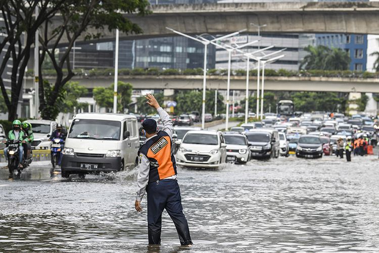 Petugas Dinas Perhubungan mengatur lalu lintas saat terjadinya banjir di kawasan Jalan Jenderal Sudirman, Jakarta, Sabtu (20/2/2021). Intensitas hujan yang tinggi serta buruknya drainase menyebabkan banjir di sejumlah wilayah Ibu Kota.