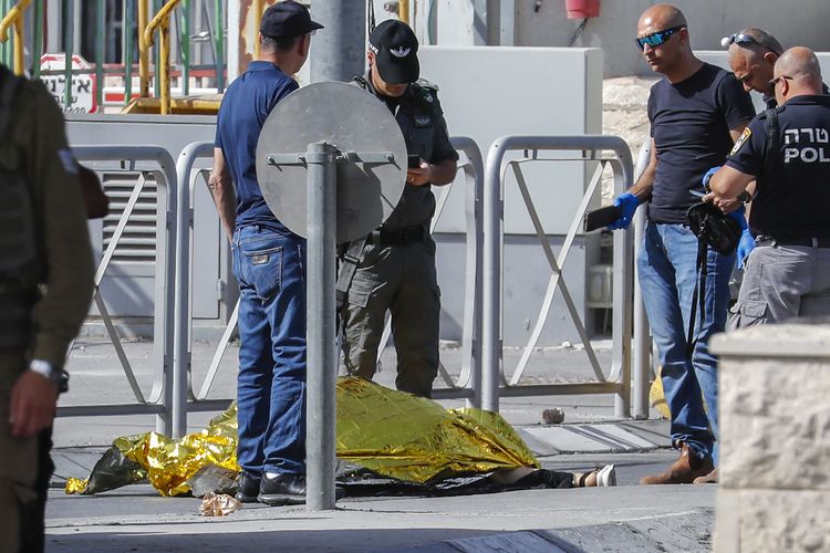 Pasukan keamanan Israel berkumpul di sekitar tubuh seorang wanita di tanah menyusul serangan yang dilaporkan di pos pemeriksaan Qalandia antara Tepi Barat yang diduduki dan Yerusalem, pada 12 Juni 2021.