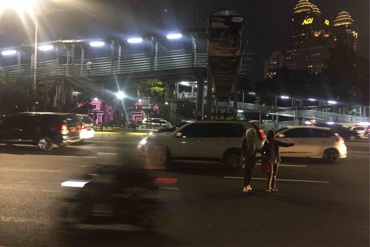 Sejumlah warga  bertaruh nyawa saat berusaha menyeberang jalan usai turun dari Jembatan Penyeberangan Orang (JPO)  Polda di Jalan Jenderal Sudirman, Jakarta Pusat, Senin (13/8/2018) malam. Pasalnya, tak ada pengamanan terhadap warga yang ingin menyeberang jalan menuju Jalan Jenderal Sudirman setelah turun dari JPO tersebut.