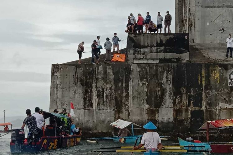Aparat kepolisian dan tim SAR dibantu warga mengevakuasi seseosok mayat pria tanpa identitas dari atas pndsasi penyanggah Jembatan Merah Putih, Ambon, Kamis siang (19/8/2021)