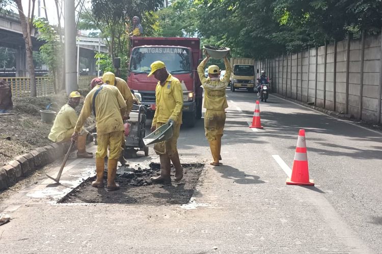 Petugas memperbaiki jalan inspeksi Ancol yang akan digunakan untuk event memfasilitasi para pebalap liar di Jakarta Utara, Selasa (11/1/2022).