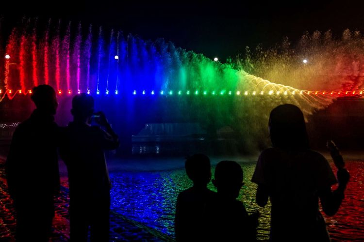 Pengunjung menyaksikan pertunjukan Semarang Bridge Fountain atau jembatan dengan air mancur menari jelang malam pergantian tahun baru di area Sungai Banjir Kanal Barat, Semarang, Jawa Tengah, Senin (31/12/2018). Pemkot Semarang secara resmi meluncurkan jembatan air mancur pertama yang ada di Indonesia senilai sekitar Rp17 miliar itu pada malam perayaan pergantian tahun baru sebagai destinasi wisata baru di kota tersebut.