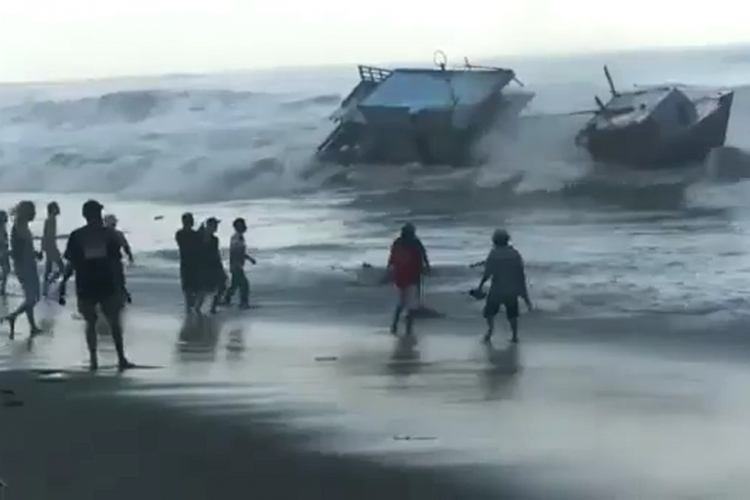 Warga berusaha mengambil ikan yang terlempar dari kapal motor Eka Sari II saat terdampar di Pantai Tegal Kamulyan, CIlacap, Jawa Tengah, Rabu (25/7/2018).