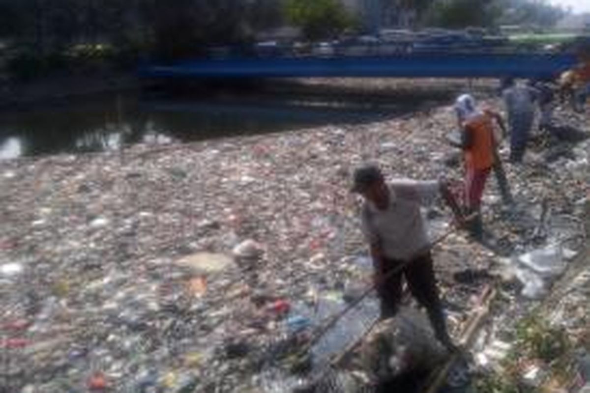 Para petugas kebersihan masih menggunakan cara tradisional untuk mengangkut sampah di sepanjang Kali Sentiong.