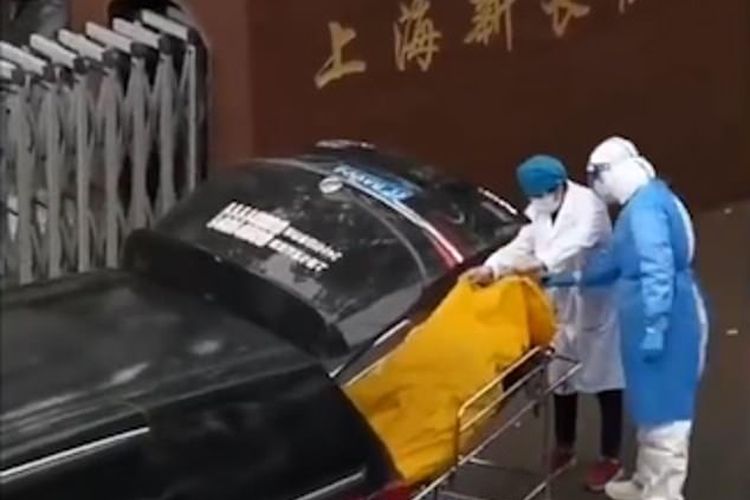 Tangkap layar video menunjukkan staf dari panti jompo Shanghai, dan pekerja kamar mayat membuka kantong mayat di bagian belakang mobil jenazah.

