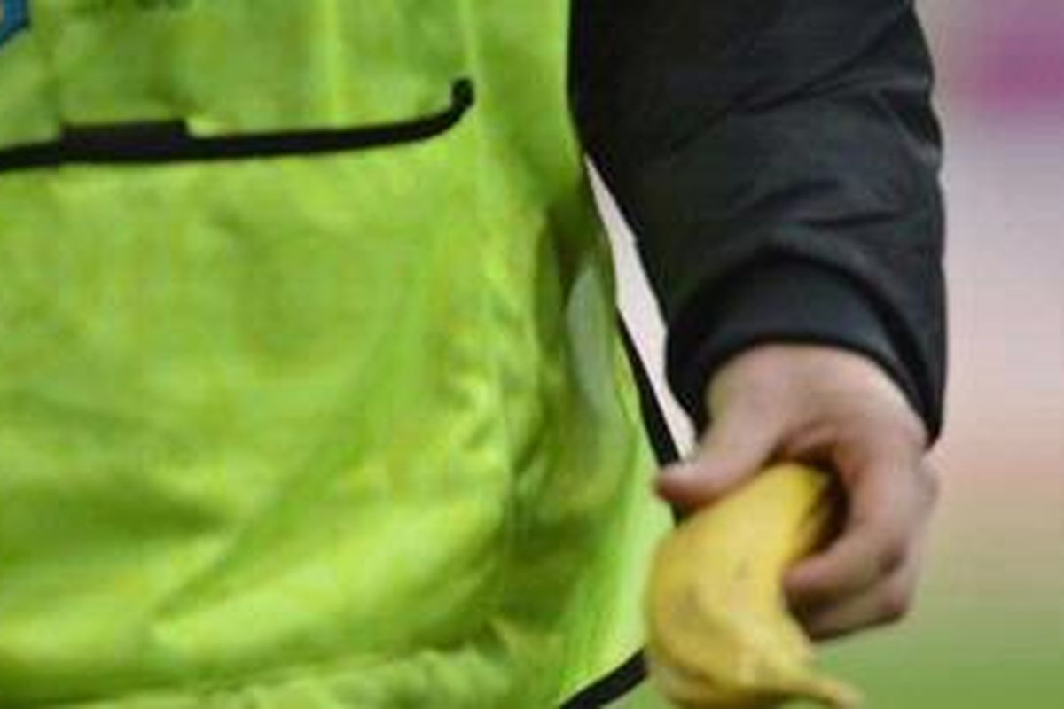 Seorang penjaga lapangan memungut pisang yang dikemparkan penonton saat laga Grup C antara Italia versus Kroasia di Stadion Municipal, Poznan, Kamis (14/6/2012). Pisang itu dipungut di bagian lapangan dimana terdapat mayoritas pendukhng Kroasia. Fotografer yang berada di sana sempat mendengar suara-suara monyet yang ditujukan untuk bomber Italia Mario Balotelli.  