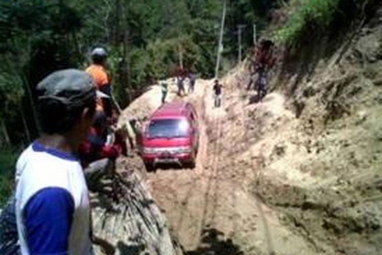 Minibus berusaha keluar dari material longsor yang menutupi akses jalan poros Kabupaten Sinjai - Kabupaten Gowa, setelah dibantu oleh sejumlah warga setempat. Kamis, (19/09/2013).