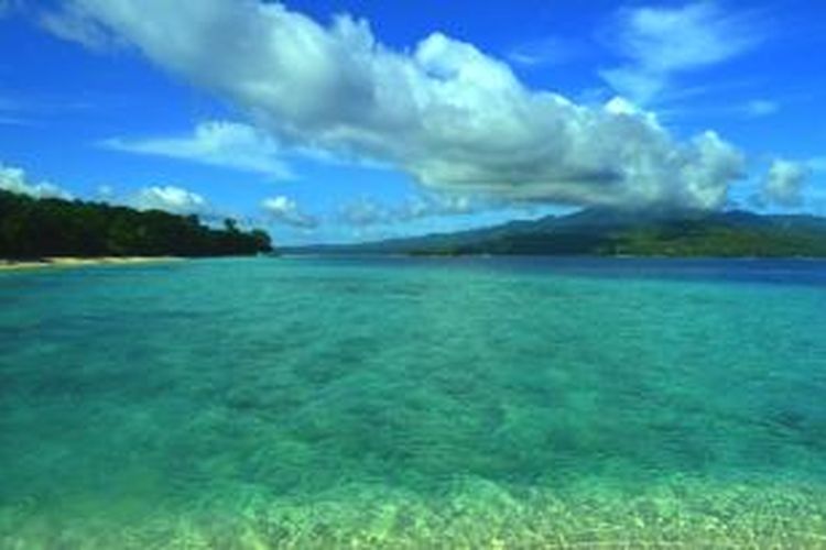 Biru air laut Pulau Pombo dengan latar Pegunugan Salahutu, Maluku. 