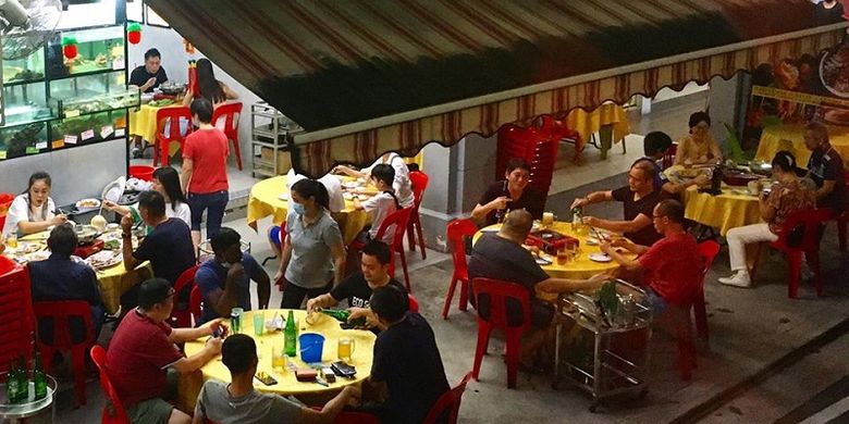 Pengunjung Restoran Seafood Tian Tian di Tiong Bahru, Singapura menunggu sambil menyantap hidangan mereka, Jumat malam (19/06/2020). Warga dapat kembali menyantap hidangan di tempat mulai Jumat hari ini yang adalah  hari pertama Fase 2 Singapura menuju new normal hidup berdampingan dengan virus Covid-19.