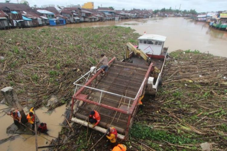 Petugas berusaha membersihkan sampah yang menutup sebagian permukaan Sungai Martapura di Kota Banjarmasin.
