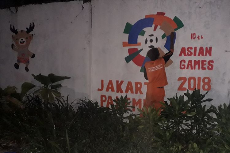 Petugas PPSU menggambar maskot Asian Games di tembok lapangan tembak Gelora Senayan, Kamis (19/7/2018)