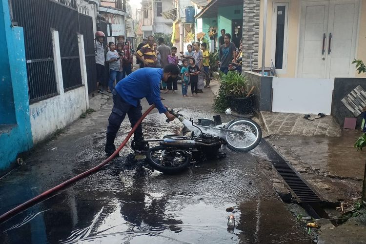 Petugas Damkar Depok tengah melakukan pendinginan usai memadamkan api yang membakar motor di Depok saat diisi bensin, Kamis (31/3/2022).