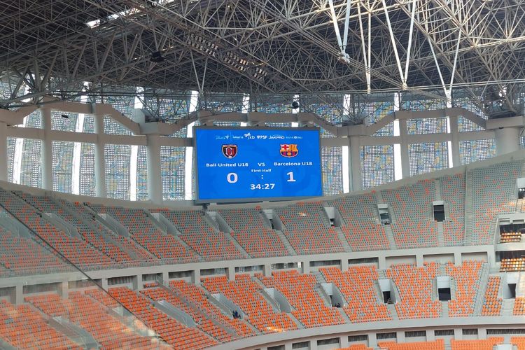 Layar videotron di Jakarta International Stadium saat menampilkan waktu dan skor pertandingan Bali United U18 vs Barcelona U18, Minggu (17/4/2022). 