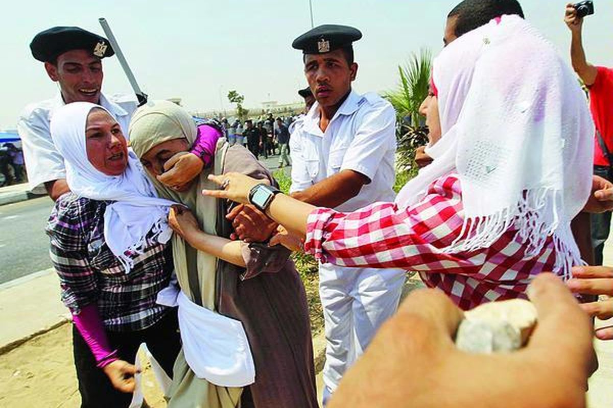 Polisi Mesir coba melerai perkelahian  dua perempuan dari kelompok antipemerintah dan seorang pendukung mantan Presiden Hosni Mubarak (tengah) di luar Akademi Polisi tempat persidangan Mubarak berlangsung, Senin (15/8).