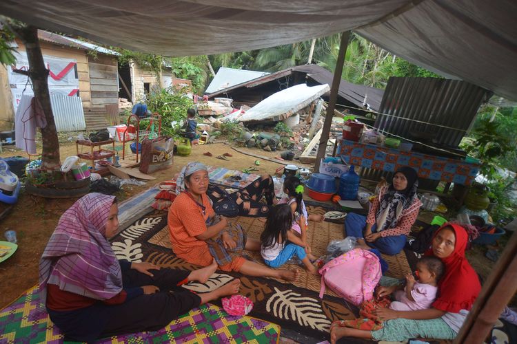 Warga berada di bawah tenda di depan rumahnya yang rusak akibat gempa di Jorong Pinagar, Nagari Aua Kuning, Kabupaten Pasaman Barat, Sumatera Barat, Jumat (25/2/2022). Badan Nasional Penanggulangan Bencana (BNPB) menyatakan gempa berkekuatan magnitudo 6,2 di Pasaman Barat dan sekitarnya itu mengakibatkan tujuh warga meninggal dunia.
