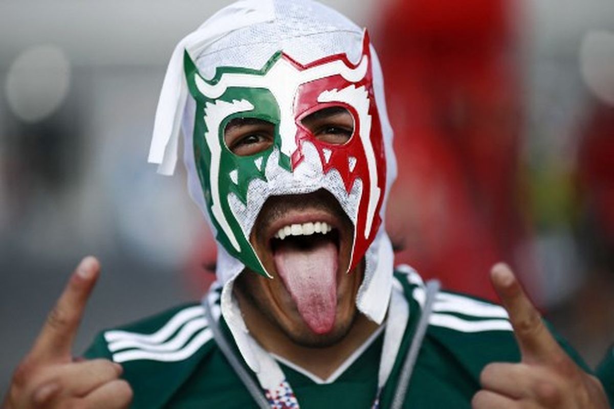 Seorang fans timnas Meksiko menggunakan topeng di Samara Arena ketika mendukung negaranya pada laga 16 besar Piala Dunia 2018 Rusia kontra Brasil. Penggunaan topeng di stadion menjadi salah satu hal yang dilarang selama Piala Dunia 2022 Qatar.