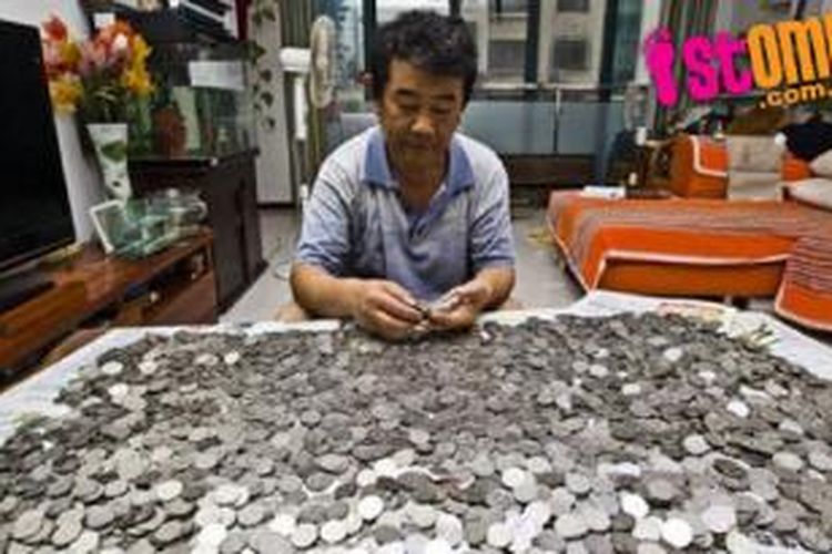 Tuan Yi menatapi tumpukan uang logam seberat 20 kg yang menjadi kompensasi atas kecelakaan yang menimpanya