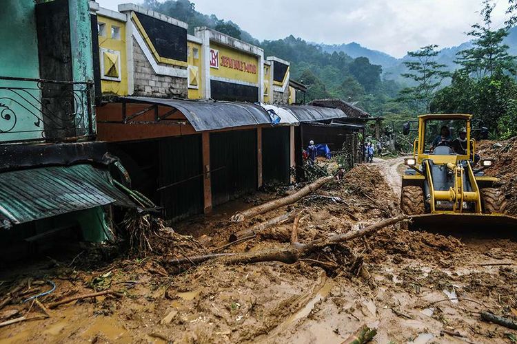 Petugas menggunakan alat berat untuk membersihkan tumpukan lumpur yang terbawa banjir di Desa Ciladaheun, Lebak, Banten, Senin (20/1/2020). Tiga pekan pasca-bencana di Lebak hingga kini masih dilakukan upaya pembersihan tanah bekas longsor terutama di daerah terisolir.