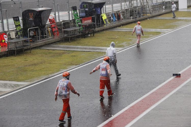 Para marshal Sirkuit Mandalika meninggalkan lapangan setelah start balapan MotoGP Indonesia 2022 ditunda akibat hujan lebat.