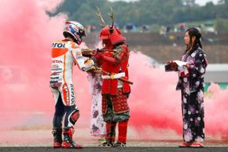 Pebalap Repsol Honda asal Spanyol, Marc Marquez (kiri), menerima pedang dari seorang samurai setelah memastikan gelar juara dunia 2014 dengan finis kedua pada GP Jepang di Sirkuit Motegi, Minggu (12/10/2014).