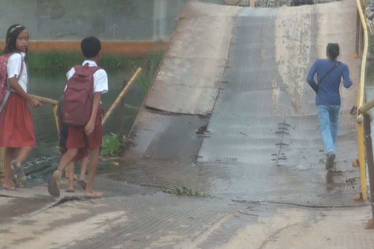 Sejumlah siswa SD di Desa Sungai Rambutan melintasi jembatan penghubung ke KTM Sungai Rambutan yang kondisinya melengkung hingga lantai jembatan mengenai permukaan air sungai. Kondisi itu sudah berlangsung satu bulan dan sangat membahayakan orang yang melintas.