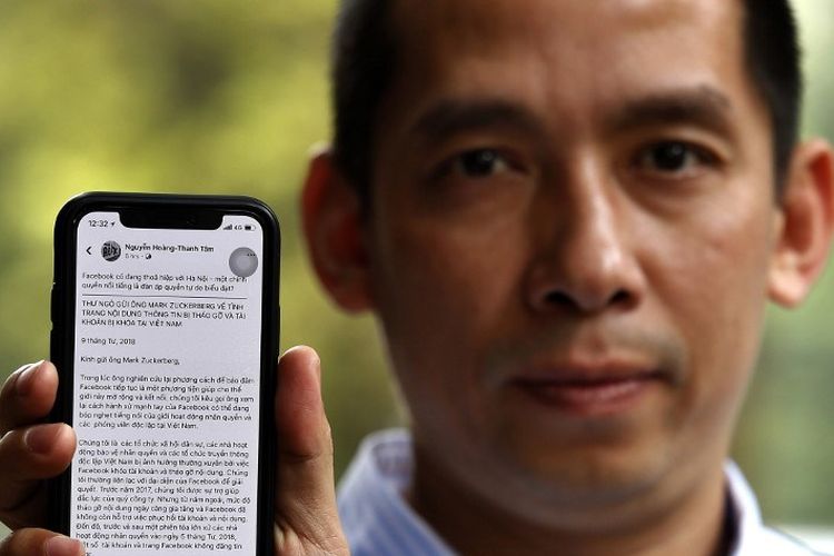 Aktivis Vietnam La Viet Dung mengangkat telepon dengan layar yang menampilkan surat terbuka kepada kepala Facebook Mark Zuckerberg di Hanoi pada 10 April 2018. - Sekelompok 50 aktivis Vietnam dan organisasi hak asasi telah menulis surat terbuka kepada kepala Facebook Mark Zuckerberg menyarankan perusahaannya mungkin berkolusi dengan otoritas komunis untuk menghapus perbedaan pendapat online. (Foto oleh - / AFP)