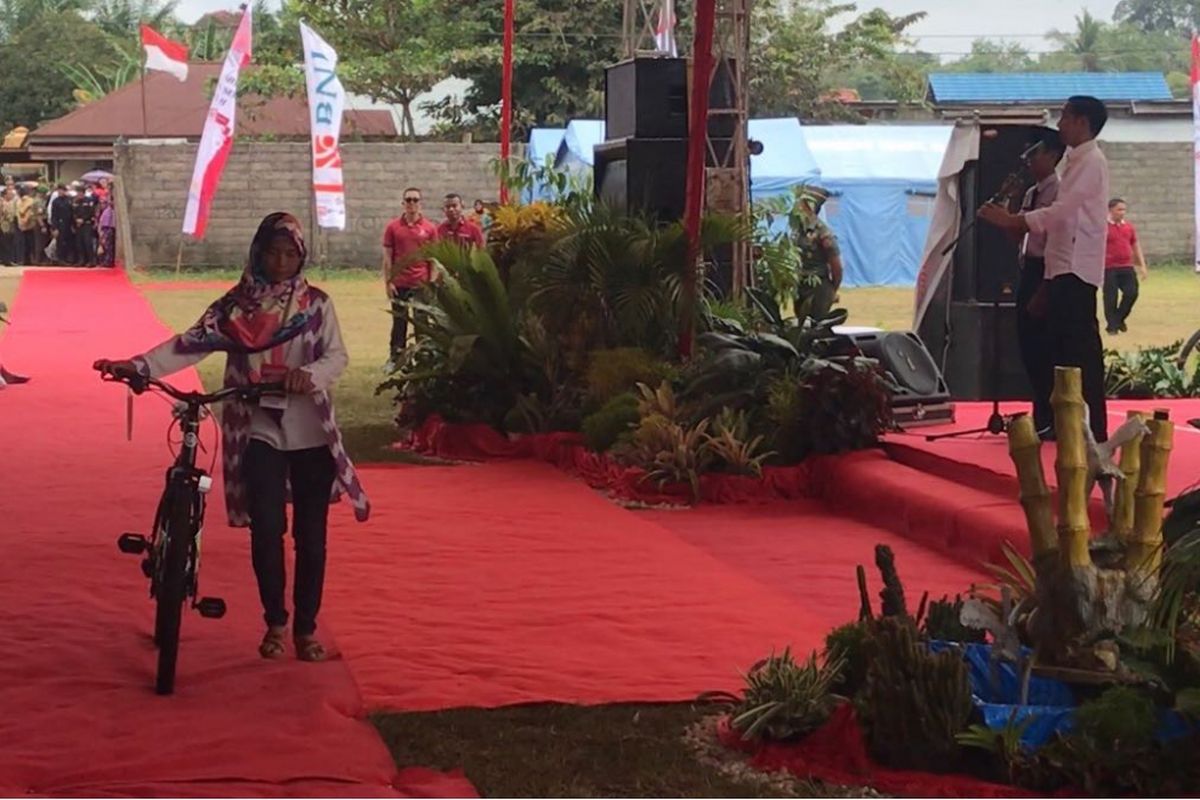Murdaliyati (47), warga Koto Baru, Kabupaten Dharmasraya membawa sepeda hadiah dari Presiden Joko Widodo. Momen itu terjadi saat Presiden membagikan Program Keluarga Harapan dan Kartu Indonesia Pintar di Kabupaten Dharmasraya, Sumatera Barat, Rabu (7/2/2018).