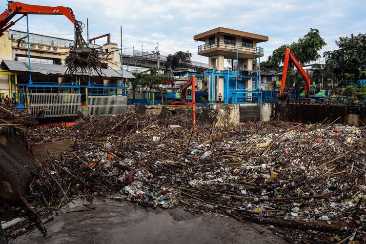 Petugas kebersihan DKI Jakarta mengangkut sampah yang terbawa arus menggunakan alat berat di Pintu Air Manggarai, Jakarta Pusat, Selasa (22/9/2020). Kenaikan muka air di Pintu Air Manggarai diakibatkan oleh hujan yang mengguyur kota Bogor dan Jakarta mulai Senin malam (21/9/2020) selama beberapa jam.