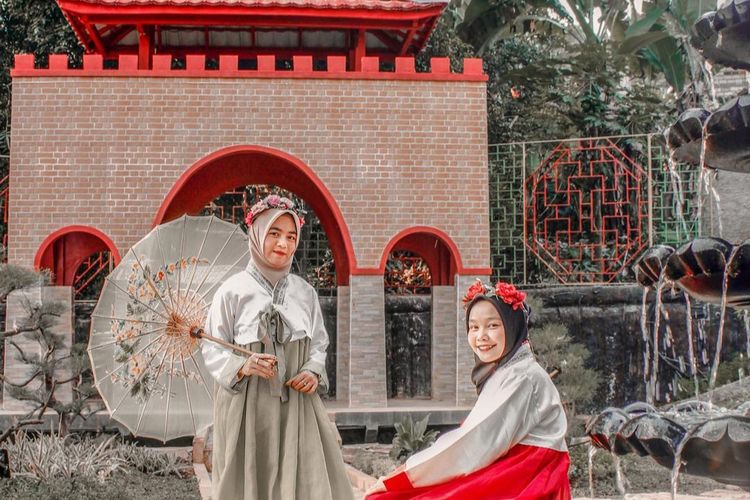 Ilustrasi pengunjung Chevilly Resort & Camp sedang berfoto dengan latar Korea Selatan sambil mengenakan hanbok.