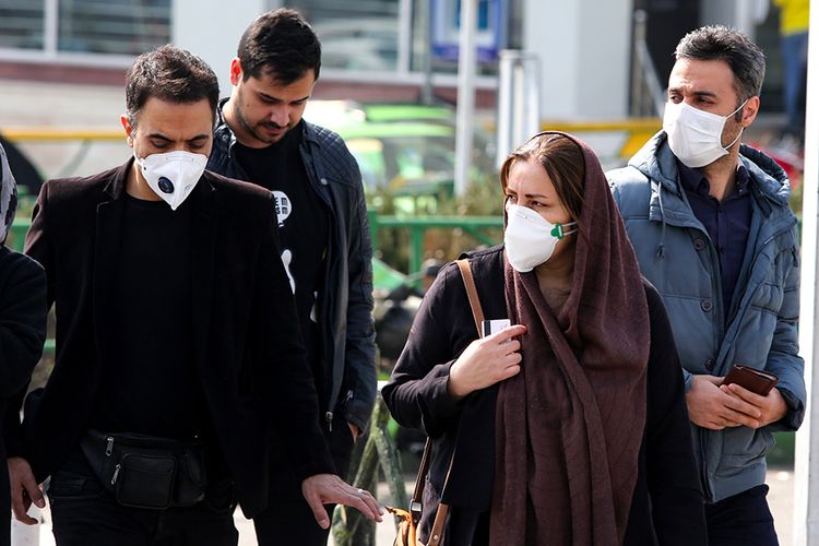 Warga mengenakan masker wajah saat hendak menyeberang jalan di daerah Tehran, Iran, menyusul bertambahnya laporan kasus corona di negara itu, Sabtu (22/2/2020). Penyebaran virus corona hingga hari ini, Senin (24/2/2020), semakin menunjukkan peningkatan di sejumlah negara, seperti Italia, Iran, dan Korea Selatan.