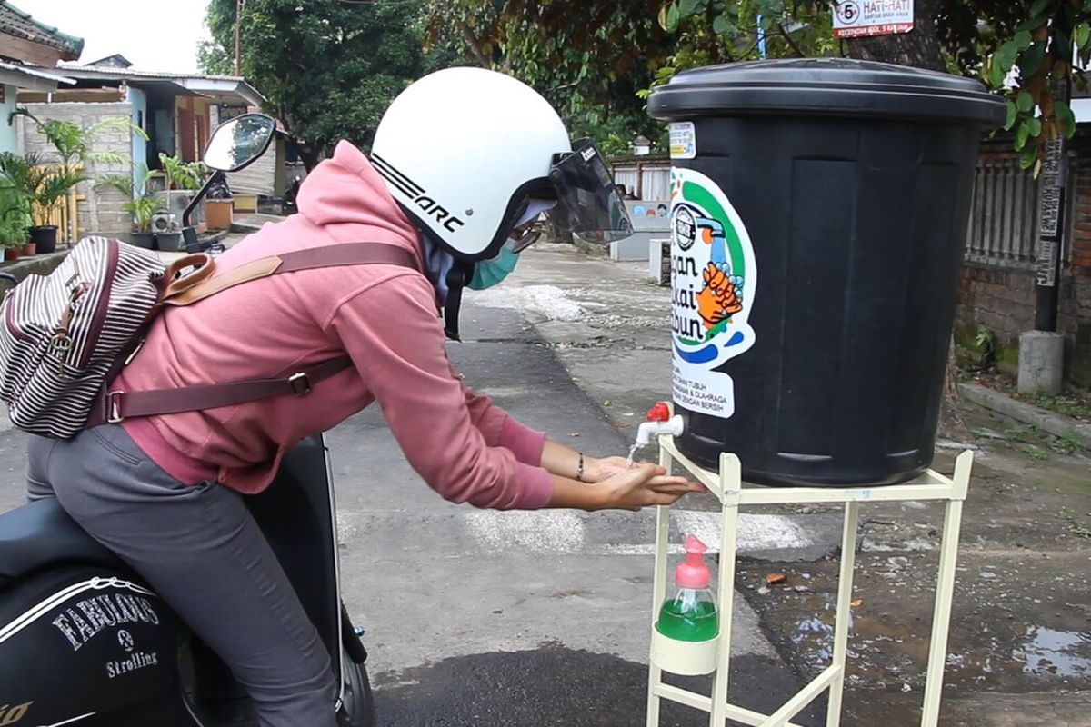 Salah seorang warga mencuci tangan di pintu masuk Lingkungan Karang Bedil, Kota Mataram yang memberlakukan  Lock Down ala kampung. Upaya ini  dipercaya bisa mengantisipasi penyebaran virus Corona Covid-19 di NTB. Angka positif corona di NTB mencapai 4 orang.