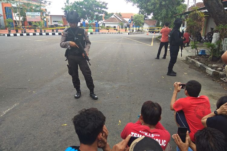 Sejumlah warga mengabadikan upaya peledakan bungkusan mencurigakan yang ditemukan di pertigaan Jl Samudra Kabupaten Magetan oleh Tim Gegana Brimob.  