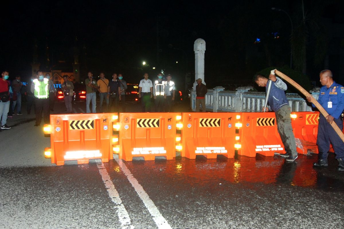 Petugas melakukan pengalihan jalur saat penutupan sebagian jalan protokol Kota Tegal, Jawa Tengah, Senin (22/3/2020) malam. Pemerintah Kota Tegal dan Polres Tegal hingga 14 hari mendatang melakukan lockdown lokal dengan menutup jalur Pantura yang melintasi Kota Tegal, akses masuk Alun-alun Tegal dan mematikan sebagian lampu jalan protokol guna pembatasan kendaraan yang akan masuk ke Kota Tegal dan mencegah adanya kerumunan massa di jalan untuk mencegah penyebaran COVID-19. ANTARA FOTO/Oky Lukmansyah/aww.