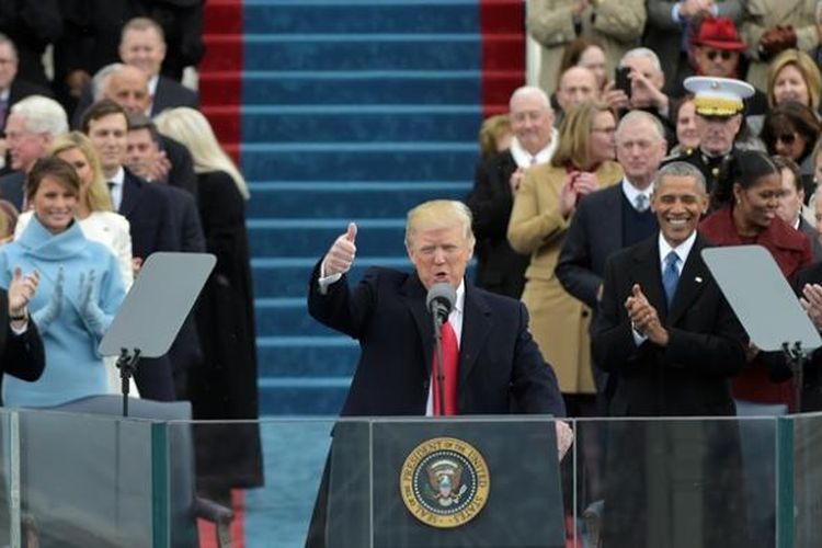 Presiden AS Donald Trump bersiap memberikan pidato beberapa saat usai dilantik pada Jumat (20/1/2017). Di belakangnya terlihat pendahulunya Barack Obama dan Joe Biden. 