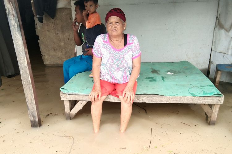 Nyamah (70) duduk di bangku diantara banjir di Desa Karangligar Kecamatan Telukjambe Barat, Kabupaten Karawang, Jumat (21/2/2020).