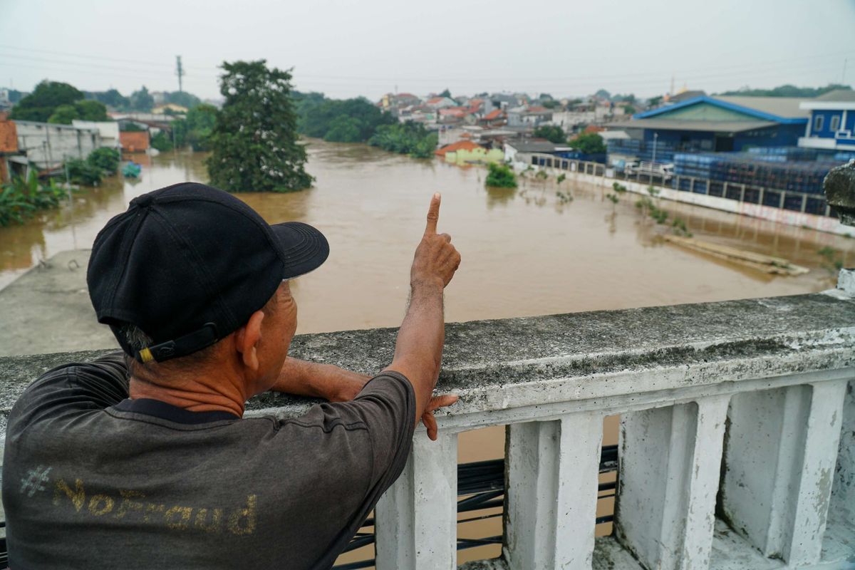 Warga menonton banjir di Kampung Cililitan Kecil, Cililitan, Jakarta Timur, Selasa (4/3/2025). Banjir disebabkan oleh meluapnya air Sungai Ciliwung setelah pada malam sebelumnya kawasan Jabodetabek diguyur hujan lebat.