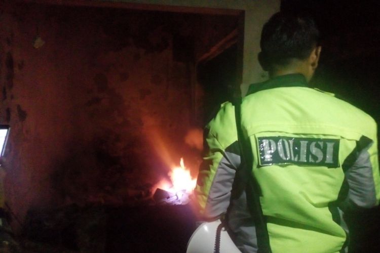 Petugas kepolisian mengawal proses pendinginan kios-kios yang terbakar