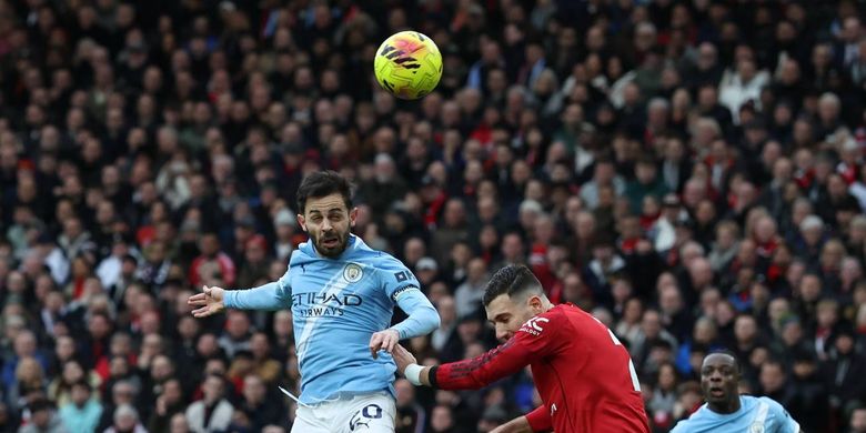 Bernardo Silva berdue udara dengan Diogo Dalot dalam pertandingan sepak bola Liga Inggris Manchester United vs Manchester City di Old Trafford di Manchester, barat laut Inggris, pada 17 Januari 2026. (Foto oleh Darren Staples / AFP) 