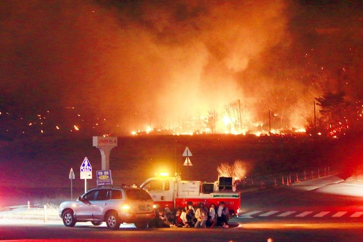 Penduduk berlindung di balik kendaraan, sementara api kebakaran melanda kawasan kota Goseong, provinsi Gangwon, Korea Selatan, pada Kamis (4/4/2019).