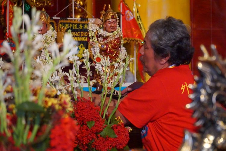 Seorang umat Tridharma sedang meletakkan patung Konco Ta Hu Com Jin di altar setelah Kiran dilakukan