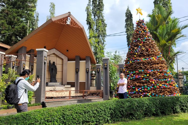 Umat berfoto dengan latar belakang pohon natal dari sabut kelapa di halaman Gereja Katedral Kristus Raja Purwokerto, Kabupaten Banyumas, Jawa Tengah, Kamis (21/12/2022).