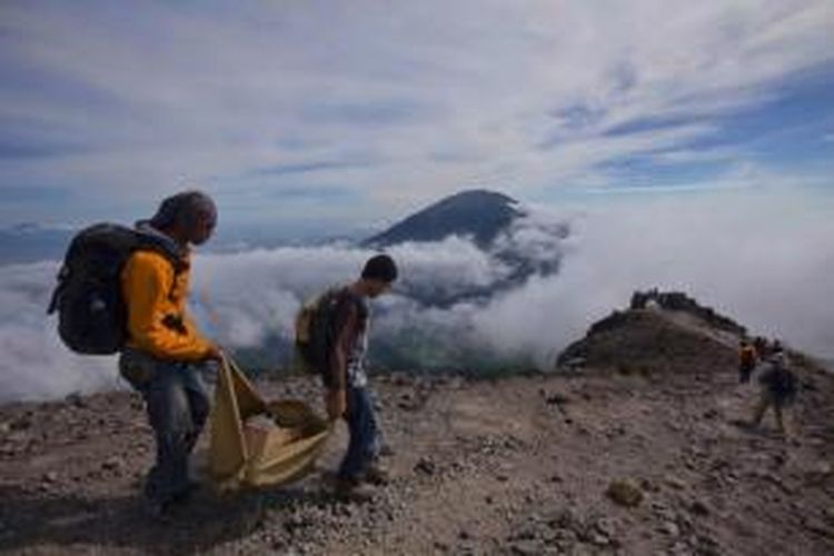 Mahasiswa Sekolah Tinggi Teknologi Mineral Indonesia menuruni Gunung Merapi (2.896 mdpl) sambil memungut sampah di jalur Selo, Boyolali, Jawa Tengah, Minggu (8/6/2014).