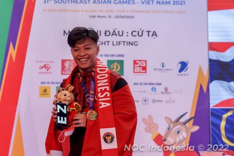 Rahmat Erwin Abdullah memamerkan medali emas cabor angkat besi yang didapatkannya di kelas 73kg putra di SEA Games 2021 Vietnam, Sabtu (21/05/2022). 