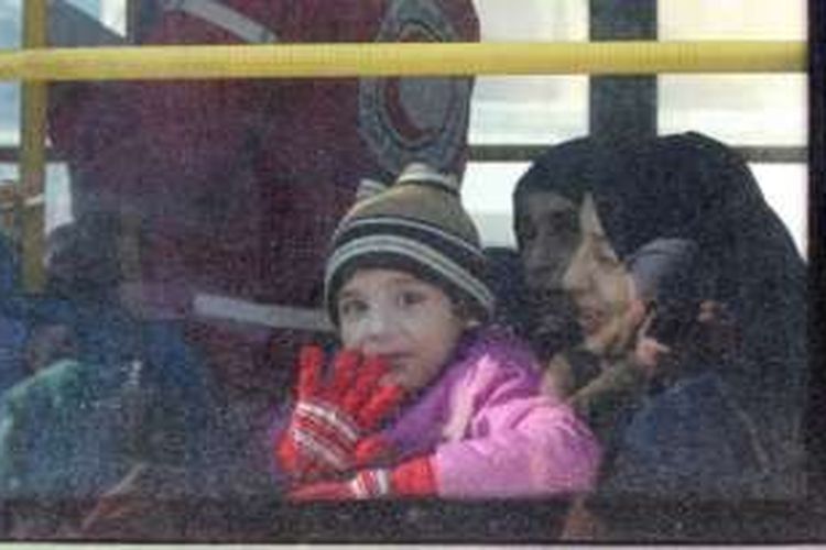 Seorang pengungsi anak dari Aleppo tersenyum dan melambaikan tangan setelah masuk ke dalam bus yang akan mengevakuasi mereka keluar dari kota yang hancur tersebut.