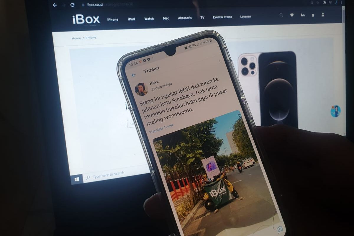 Pengguna Twitter dengan handle @dewahoya, mengunggah foto spanduk iBox dan iPhone 12 yang terpajang di tepi jalan di daerah Surabaya.