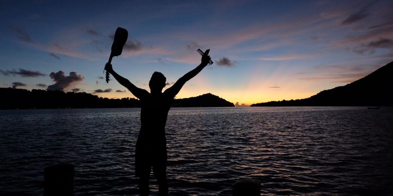 Wisatawan berpose di pemandangan senja, Pulau Banda Neira.